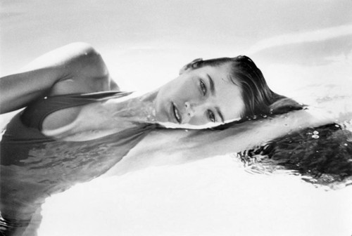 Fashion shoot at the pool with model swimming laps