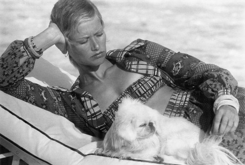 1970\'s fashion shoot relaxing at the pool with cute white fluffy puppy
