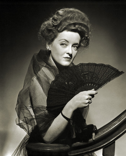 Bette Davis in black dress on the stairs by George Hurrell.