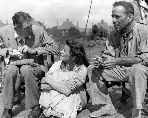 Production Still taken on location for the film African Queen, Director John Huston with Humphrey Bogart and Katharine Hepburn, the co-stars of THE AFRICAN QUEEN. This informal picture was taken at Orton Hall Studios where interior shots were filmed for a Screen version of the CS Forester novel. The exteriors were shot against natural backgrounds in the Belgian Congo and Uganda.