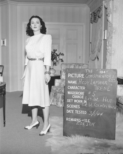 Hedy Lamarr stands frozen in this intriguing test shot. Early in the filming of The Conspirators Hedy learned she was pregnant , and some critics have used that to label her performance laconic or disinterested. But Hedy had already elevated "I’m bored but glamorous" style into her own art form. The crowds loved the film and Warner had a hit. 

Leah Rhodes designed the costumes, and almost every reviewer of this film, both past and present, comments how great Hedy looks in those gowns. Four years after this film, Leah went on to win the first Oscar given for costumes in a color film for The Adventures of Don Juan.