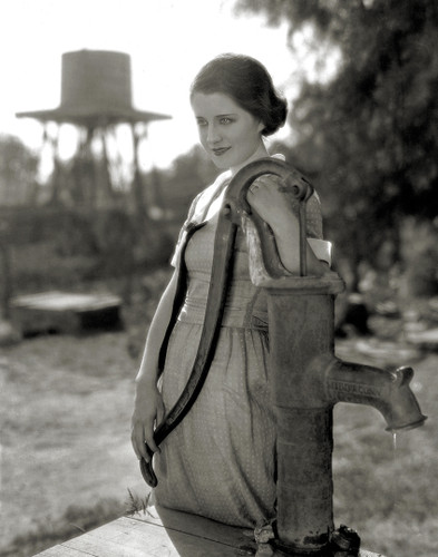 Scene still of Norma Shearer standing by the water pump in The Snob, 1924.