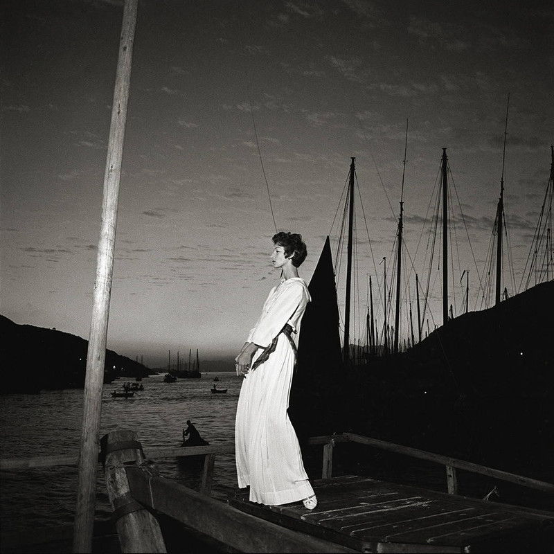 Kowloon by Gleb Derujinsky | Vintage Fashion Photo. Model on a boat dock wearing white at dusk