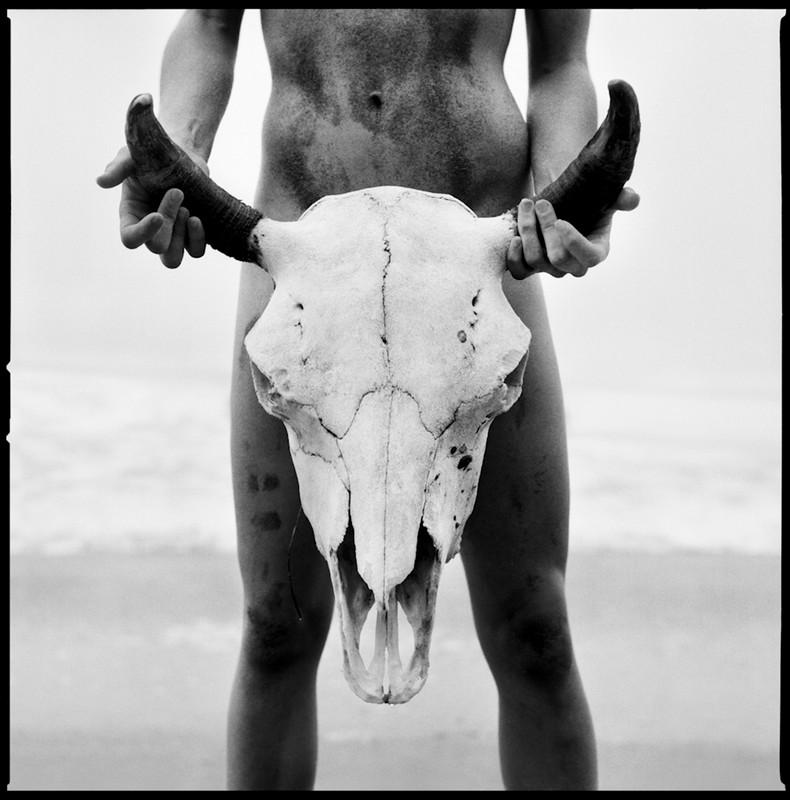 nude model holds a bull's skull on the beach in Malibu