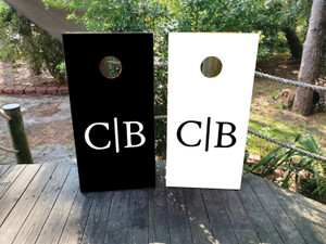 Minimalist black and white cornhole boards featuring a modern split monogram design with bold initials. Perfect for weddings, corporate events, and elegant outdoor gatherings