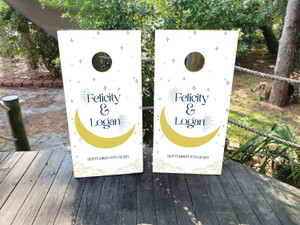 Custom celestial wedding cornhole boards featuring a white background with a golden crescent moon, stars, and personalized names. Perfect for moon and stars-themed weddings, engagement parties, and romantic outdoor celebrations