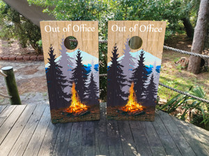 Custom camping-themed cornhole boards featuring a rustic forest design with a campfire, mountain backdrop, and 'Out of Office' text. Perfect for outdoor enthusiasts, campers, and nature lovers Custom camping-themed cornhole boards featuring a rustic forest design with a campfire, mountain backdrop, and 'Out of Office' text. Perfect for outdoor enthusiasts, campers, and nature lovers