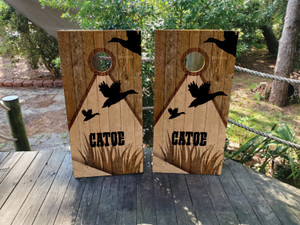 Custom duck hunting-themed cornhole boards featuring a rustic wood background, flying duck silhouettes, reeds, and a personalized name. Perfect for hunters, outdoor enthusiasts, and cabin decor Custom duck hunting-themed cornhole boards featuring a rustic wood background, flying duck silhouettes, reeds, and a personalized name. Perfect for hunters, outdoor enthusiasts, and cabin decor