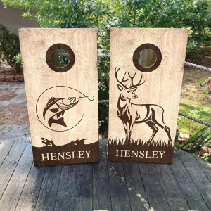 Custom rustic cornhole board wraps featuring a woodgrain background with detailed hunting and fishing designs. One board showcases a jumping fish with a fishing line, while the other highlights a majestic buck. Personalized with a family name, these high-quality, weatherproof vinyl wraps are perfect for outdoor enthusiasts, hunters, and anglers Custom rustic cornhole board wraps featuring a woodgrain background with detailed hunting and fishing designs. One board showcases a jumping fish with a fishing line, while the other highlights a majestic buck. Personalized with a family name, these high-quality, weatherproof vinyl wraps are perfect for outdoor enthusiasts, hunters, and anglers