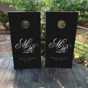 Custom monogram wedding cornhole boards featuring a black background with elegant white script initials, personalized names, and an established date. Perfect for weddings, anniversaries, and formal celebrations. Custom monogram wedding cornhole boards featuring a black background with elegant white script initials, personalized names, and an established date. Perfect for weddings, anniversaries, and formal celebrations.