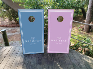Pastel wedding cornhole board wraps in lavender and dusty blue, featuring minimalist double-line borders and elegant script that reads “The Basistas – Est. 2025.” A soft, modern design perfect for romantic outdoor weddings, spring celebrations, or garden receptions.