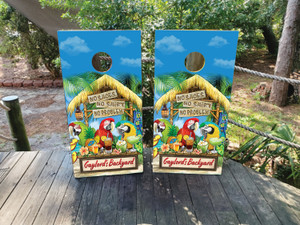 Tropical tiki hut-themed cornhole wrap featuring colorful parrots, palm leaves, tropical drinks, a thatched roof sign reading “No Shoes No Shirt No Problem,” and customizable wooden sign text at the bottom.