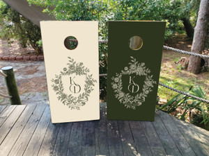 Elegant floral monogram design featuring a hand-drawn crest with roses, ribbon details, and custom initials on cream and dark green backgrounds.