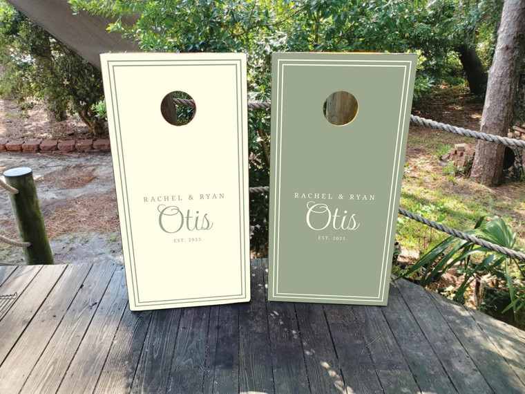 Elegant olive green and ivory wedding cornhole board wraps featuring personalized text that reads “Rachel & Ryan Otis – Est. 2025.” The minimalist double-border design combines classic typography with modern simplicity, creating a timeless look perfect for wedding receptions, anniversaries, or engagement celebrations.