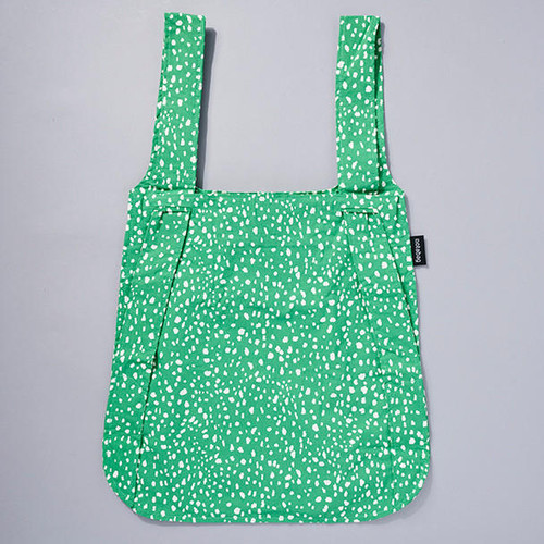 Backpack tote in kelly green with overall white dot pattern, tote bag styling, lying flat, view of backpack straps.
