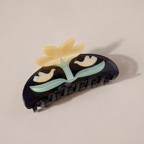 Semi-circle shaped Twin Doves White Lotus Acetate Hair Clip with 4 pointed white lotus on top above a green stem with 2 green leaves on either side and a dove above each leaf facing each other on a dark brown background