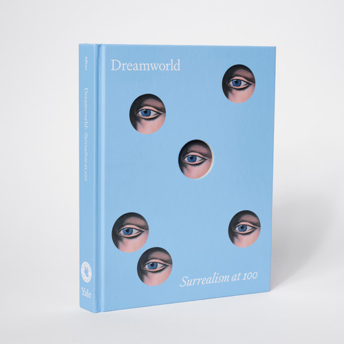 The front cover of "Dreamworld: Surrealism at 100 Exhibition Catalog", which shows 6 randomly arranged circular cutouts revealing a painting of an eye.