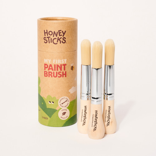 Front facing view of brown paper cylindrical package next to 3 standing paintbrushes with wood knob handles.