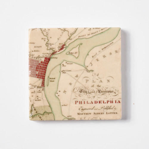 An aerial view of a tile featuring a very old map of the Philadelphia and New Jersey, divided by the Delaware River. In script it says, "Plan of the City and Environs of Philadelphia Engraved and Published by Matthew Albert Lotter". The background of the map is tan, the river is light green, and the city of Philadelphia is articulated by red rectangles in a grid formation.