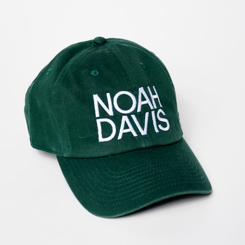 Dark green baseball cap with NOAH DAVIS text embroidered in white above bill