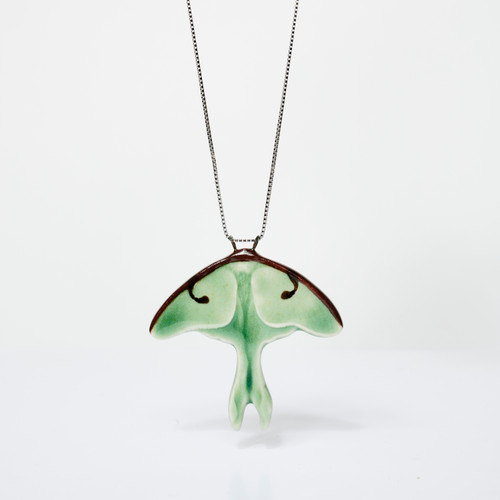 Green luna moth-shaped ceramic pendant hanging from silver chain