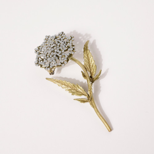 A gold brooch in the shape of a Queen Anne's Lace flower with a crystal dust finish.