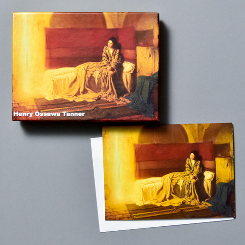 A cardboard box with a painting of a woman in a robe sitting on a bed looking at a streak of golden light is shown next to a notecard with the same painting and a white envelope.