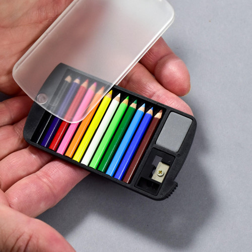 The mini color pencil set is shown flat in a model's hand for scale. The plastic protective sleeve is featured to the side. In view and placed inside the packaging are 12 colored pencils, a grey eraser and a small sharpener.