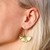 Bronze gold-toned gingko shaped dangle earrings shown on ear