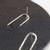 Inverted U-shaped sterling silver post style earrings with one earring upside down showing post