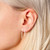 Inverted U-shaped sterling silver post style earring shown on ear