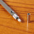 This partial view of the mechanical pencil shows the metal cover and exposes the white replaceable eraser.  The pencil lies on a wooden surface.