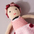 Image features a close-up crocheted ballerina doll with flowers in her brown hair and a pink tutu.