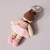 Back of Ballet Dancer Crocheted Keyring/Bag Charm shown flat with key ring wearing a tutu of primarily pink tones with brown hair and pink ballet slippers