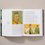 A spread of Van Gogh: The Complete Paintings shows a self-portrait of the artist in a yellow coat on the left page and two paintings of a woman seated with a child in her arms on the right page.