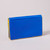 A cobalt blue envelope wallet with yellow contrast edging stands closed on a grey surface.  Its exterior back slip pocket is visible here.