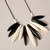 Detail of necklace of oblong alternating black and cream beads arranged in a semi-circle and strung on black cording shown laying flat