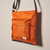 Detail of orange nylon crossbody bag at angle showing thickness of bag
