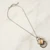 Light tan faceted diamond-shaped Artisan Glass pendant with clear glass segment below hanging from dark metal open style link chain