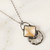 Detail of light tan faceted diamond-shaped Artisan Glass pendant with clear glass segment below hanging from dark metal open style link chain