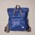 Front of Canfield Nylon Backpack in medium blue with grey handles and straps, zip front patch pocket, and small white sewn on label on lower right of front