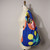 Blossom cobalt blue background with orange, yellow and green flower graphics Convertible Backpack Tote by Notabag  shown on dress form's shoulder for scale