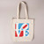 White canvas tote bag featuring printed red, light blue and white Robert Indiana "LOVE" printed on front which has 'L' and 'O' above the 'V' and 'E'
