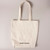 Back of white canvas tote bag featuring printed ROBERT INDIANA printed at base in black