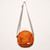 Round Nylon Crossbody Bag in Orange with grey strap, front zip pocket and small white manufacturer's sewn on label at lower right
