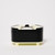 Side view of oval shaped small acrylic box with black sides and removable top of white, black and ivory with slim ivory base and small ivory-tone feet