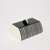 Rectangular, dome-shaped acrylic box with striped pattern design on sides and a black lift top with a small semi-circle handle of green and white, and white ends of box
