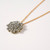 Round sparkly pendant consisting of tiny 'pedals' covered in glitter-like dust on twisted gold-tone chain shown at angle