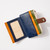 Multicolor wallet with brown snap band over navy, green and yellow orange dividers and zip top shown unsnapped with clear ID window visible
