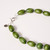 Detail of bold necklace featuring the silver-toned lobster clasp and round green beads